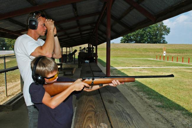 boy aiming rifle at shooting range