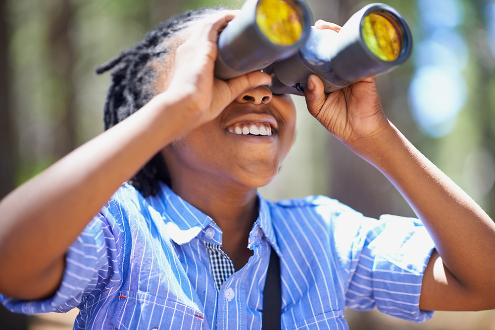 child looking through binoculars outside