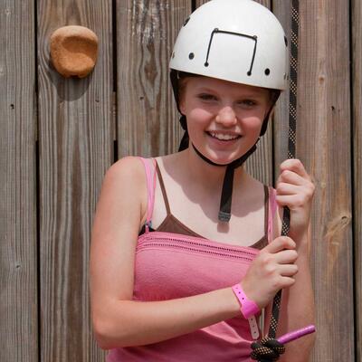 teenage girl wearing a helmet, getting ready to climb rock wall