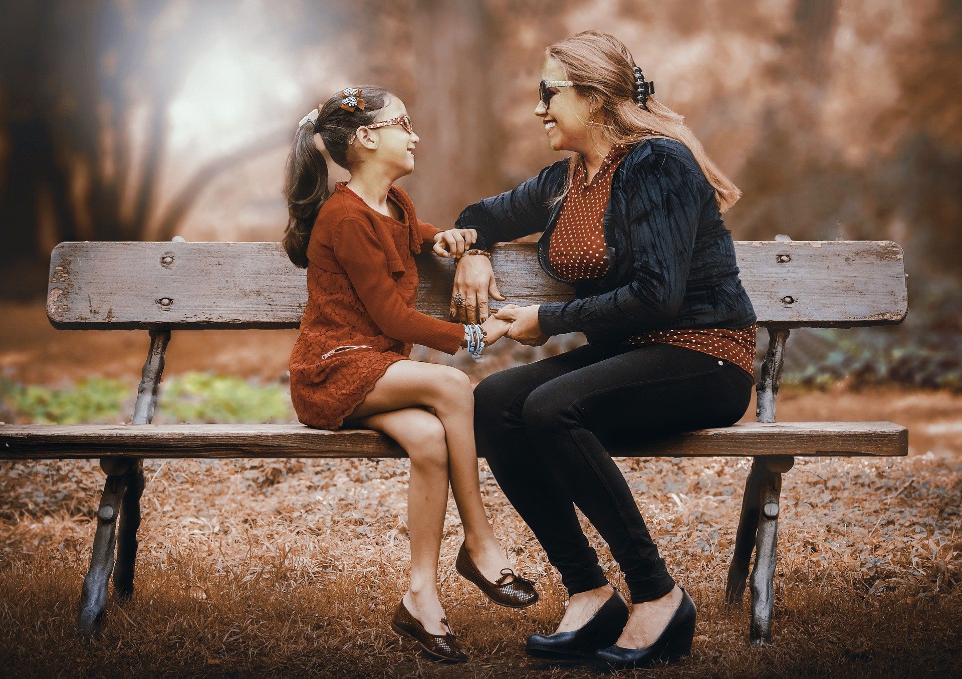 Mother talking with daughter on park bench