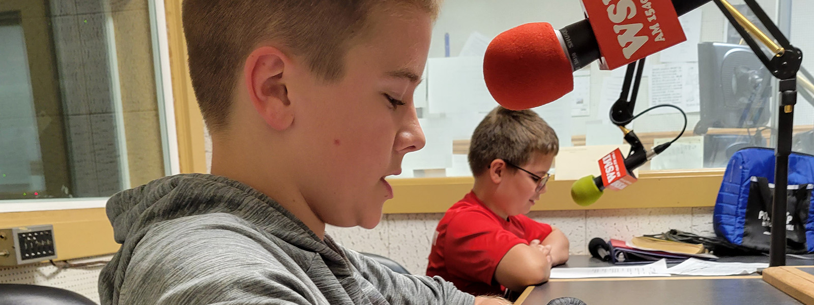 2 boys speaking into microphones in radio station