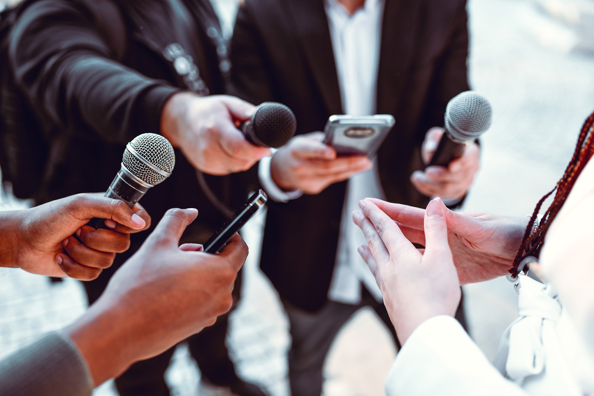 hands holding microphones and cell phones