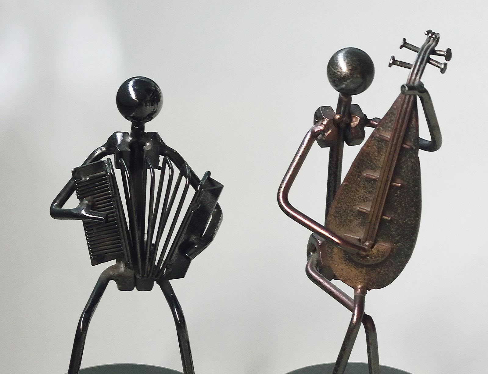 two metal people sculptures playing instruments