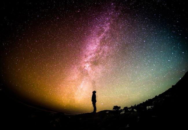 Night sky lit up and person silhouetted 