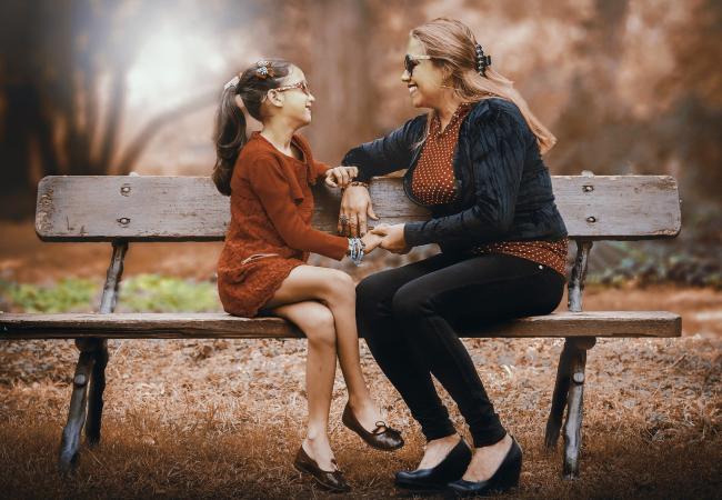 Mother talking with daughter on park bench