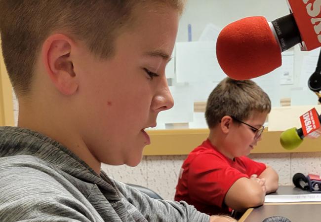 2 boys speaking into microphones in radio station