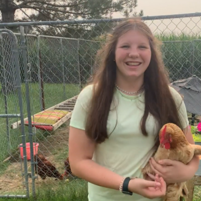Girl giving virtual farm tour holding a chicken