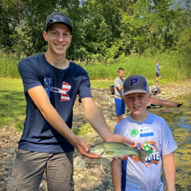 boys show fish they caught on edge of lake