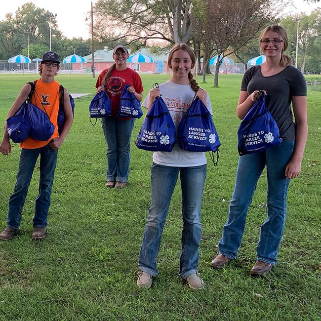 4-h teens with bags of food to distribute