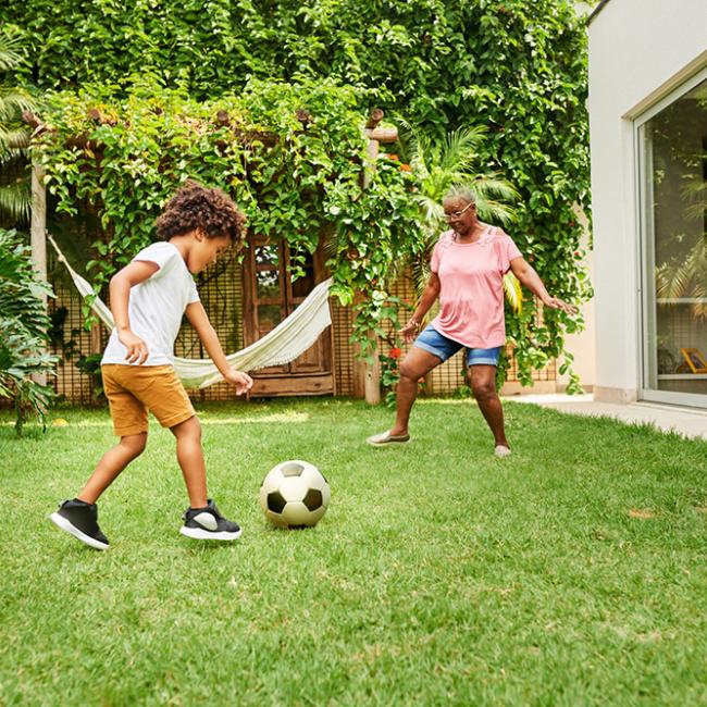 boy and grandmother playing soccer in backyard