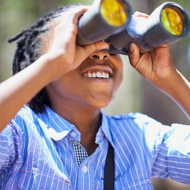 child looking through binoculars outside