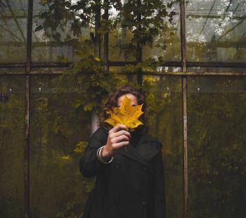 Girl holding large leaf in front of face