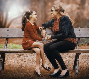 Mother talking with daughter on park bench