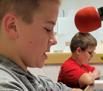 2 boys speaking into microphones in radio station