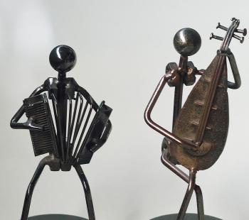 two metal people sculptures playing instruments