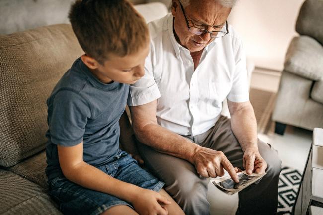 boy and grandfather look at photos together