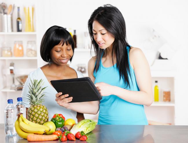 2 women look at food ideas on a tablet