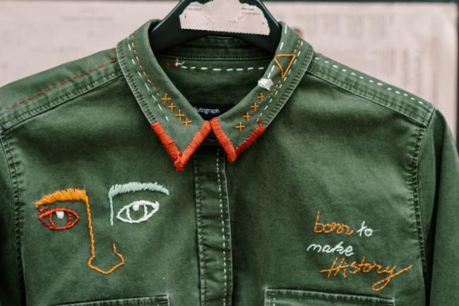 green shirt with embroidered embellishments on it that say "born to make history"