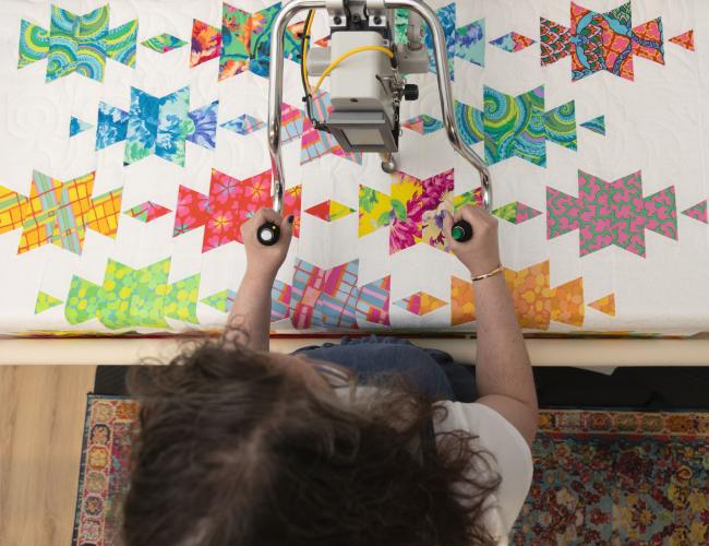 person using a quilting machine on a colorful quilt